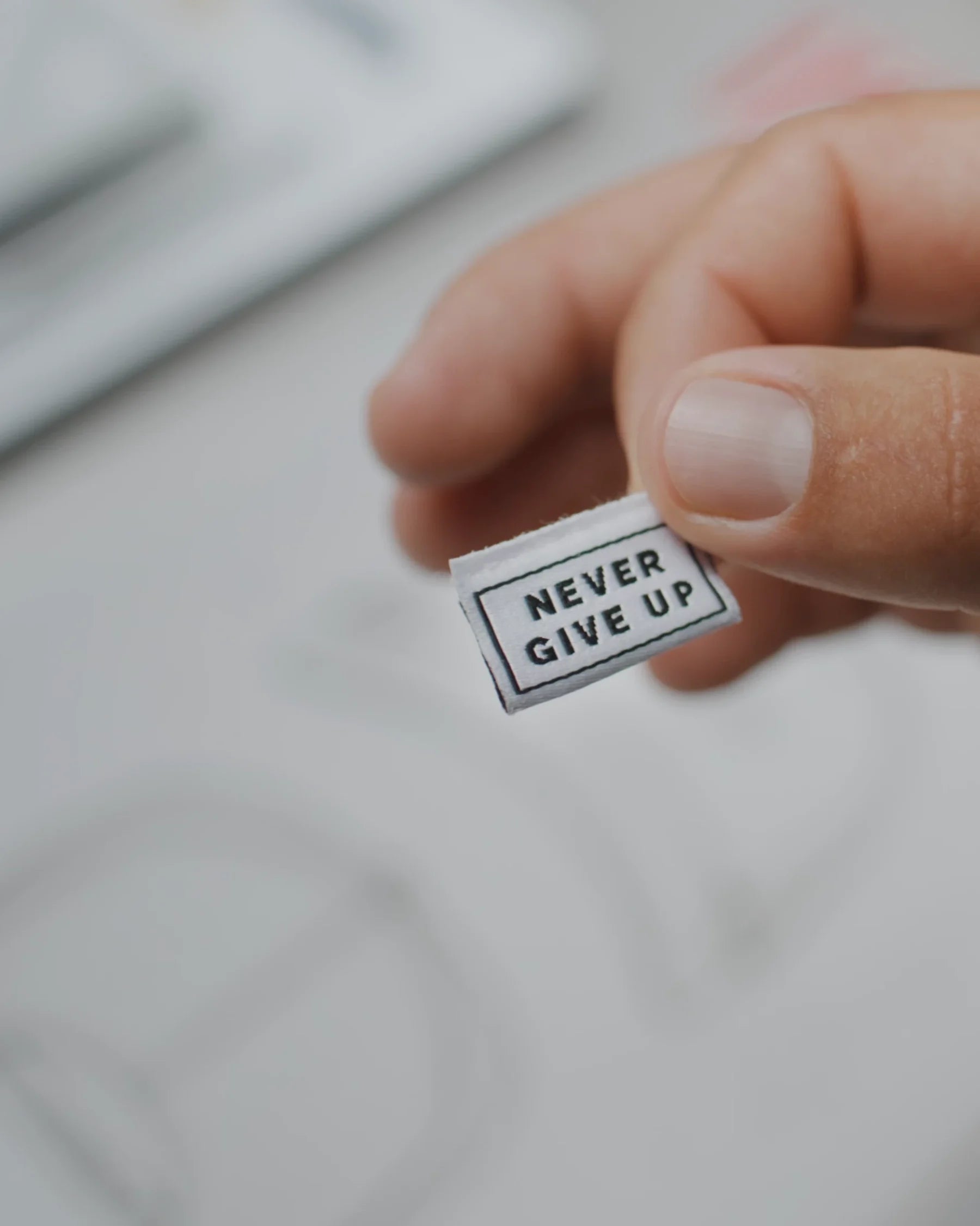 Never Give Up label between fingers